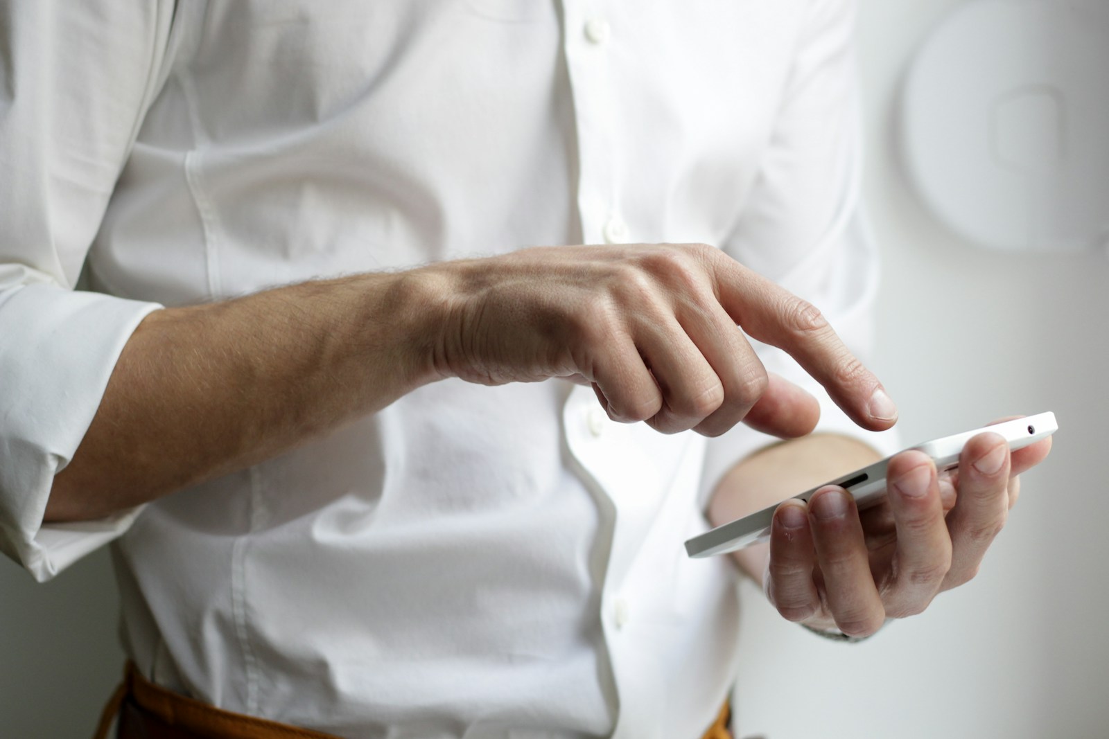 Photo by NordWood Themes person holding white Android smartphone in white shirt