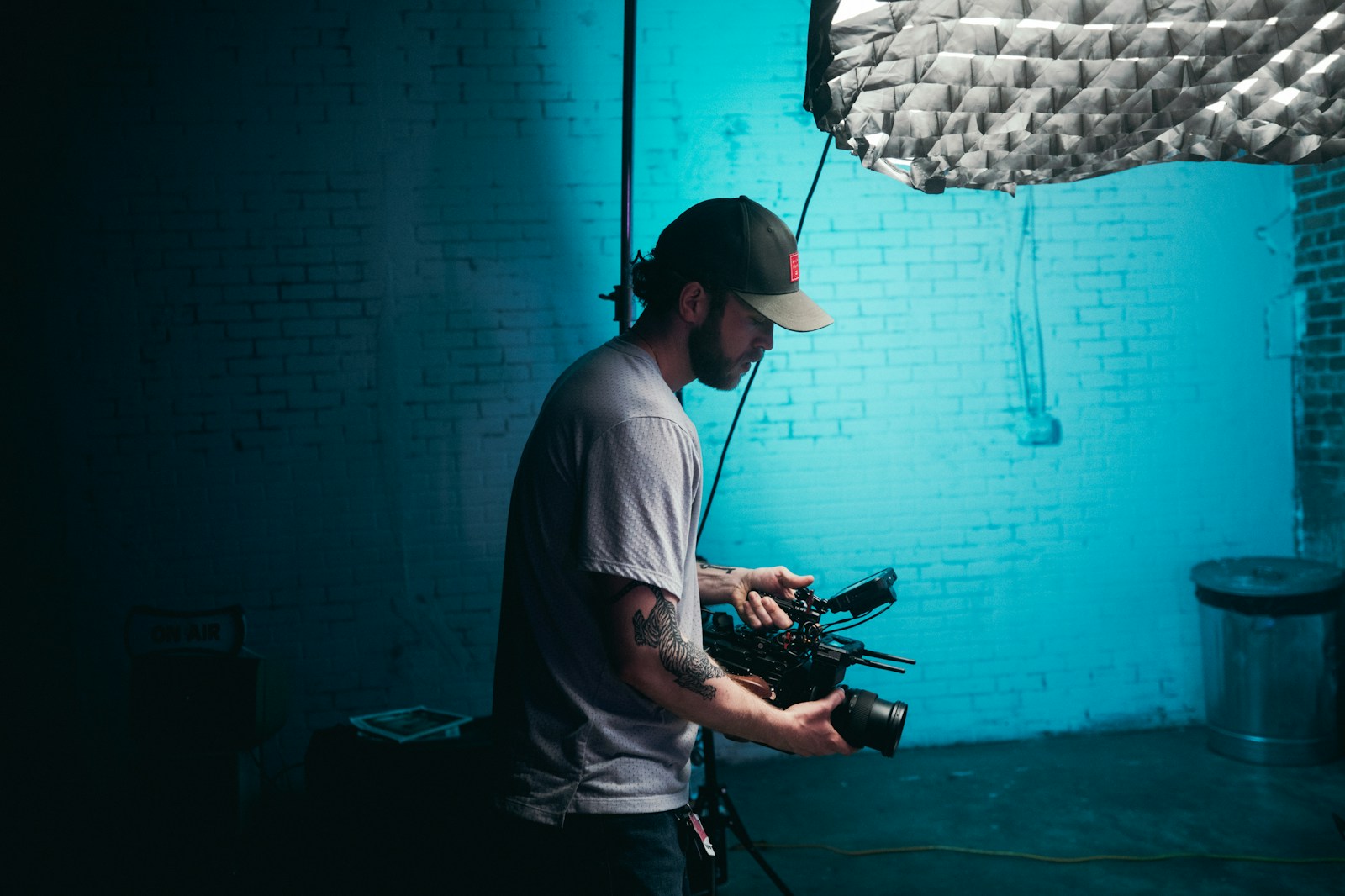 Photo by KAL VISUALS man in white crew neck t-shirt holding black dslr camera